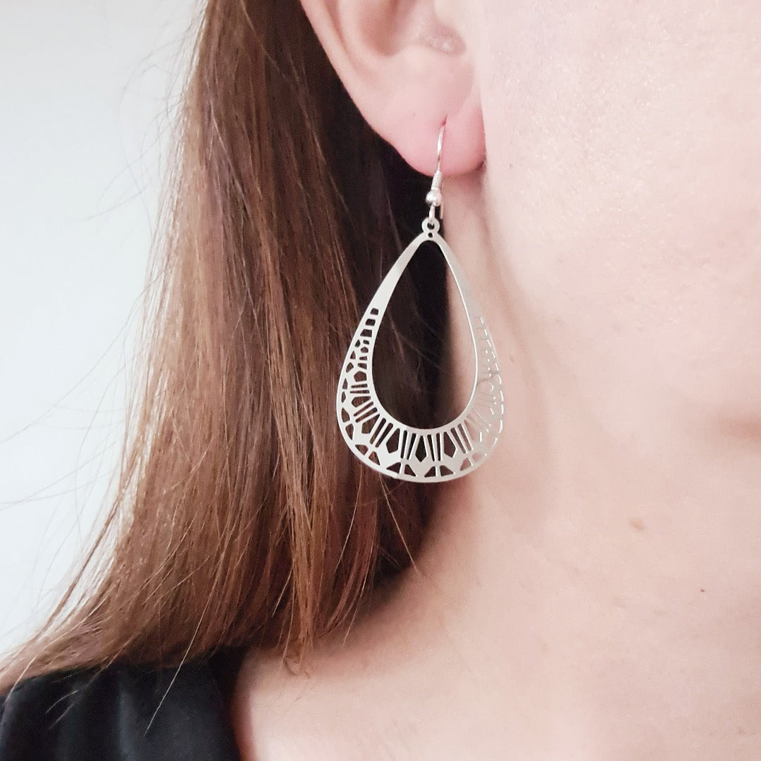 Zilverkleurige druppel oorbellen met verfijnde opengewerkte afwerking