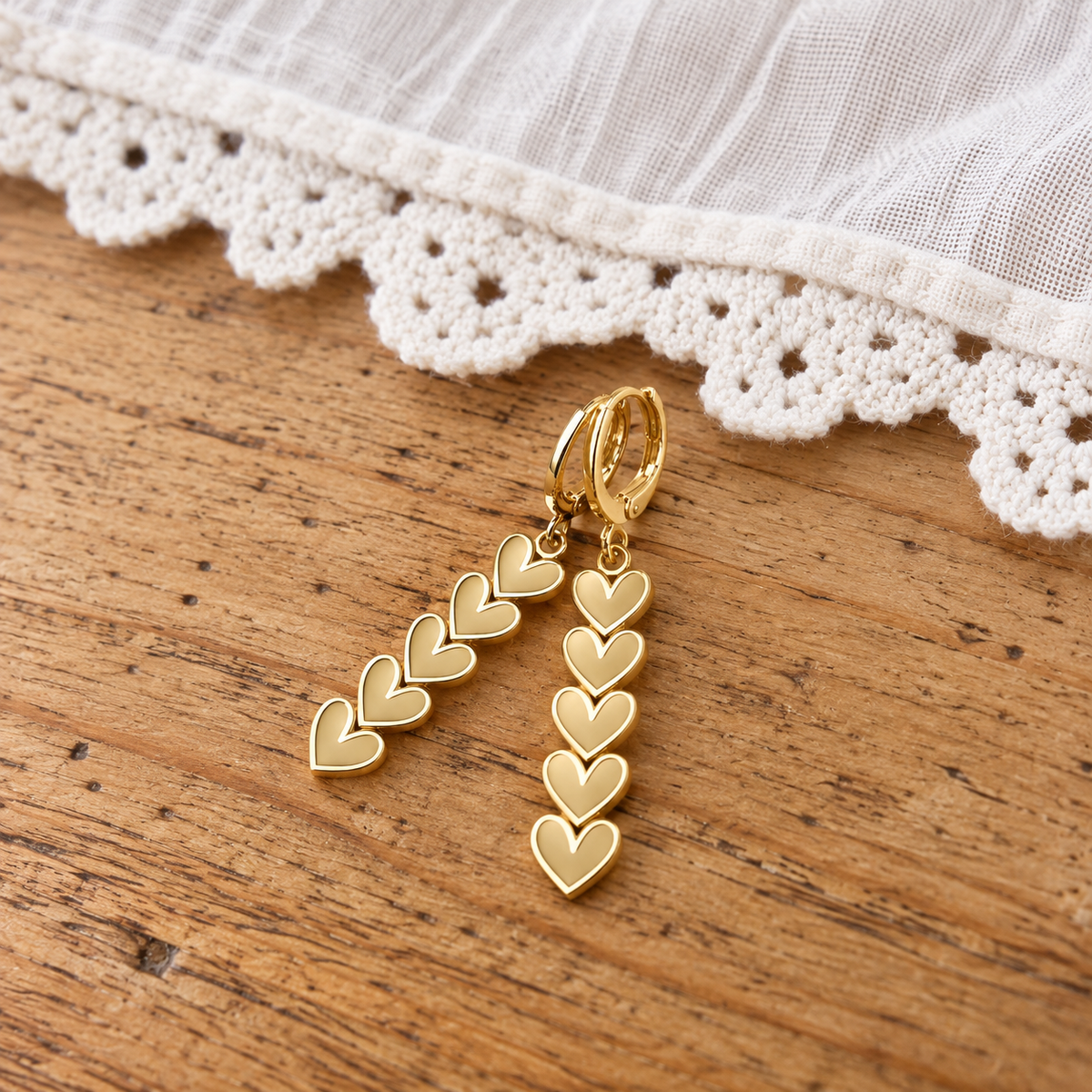 Goudkleurige oorbellen met metalen ringetjes en een stainless steel hanger met vijf hartjes