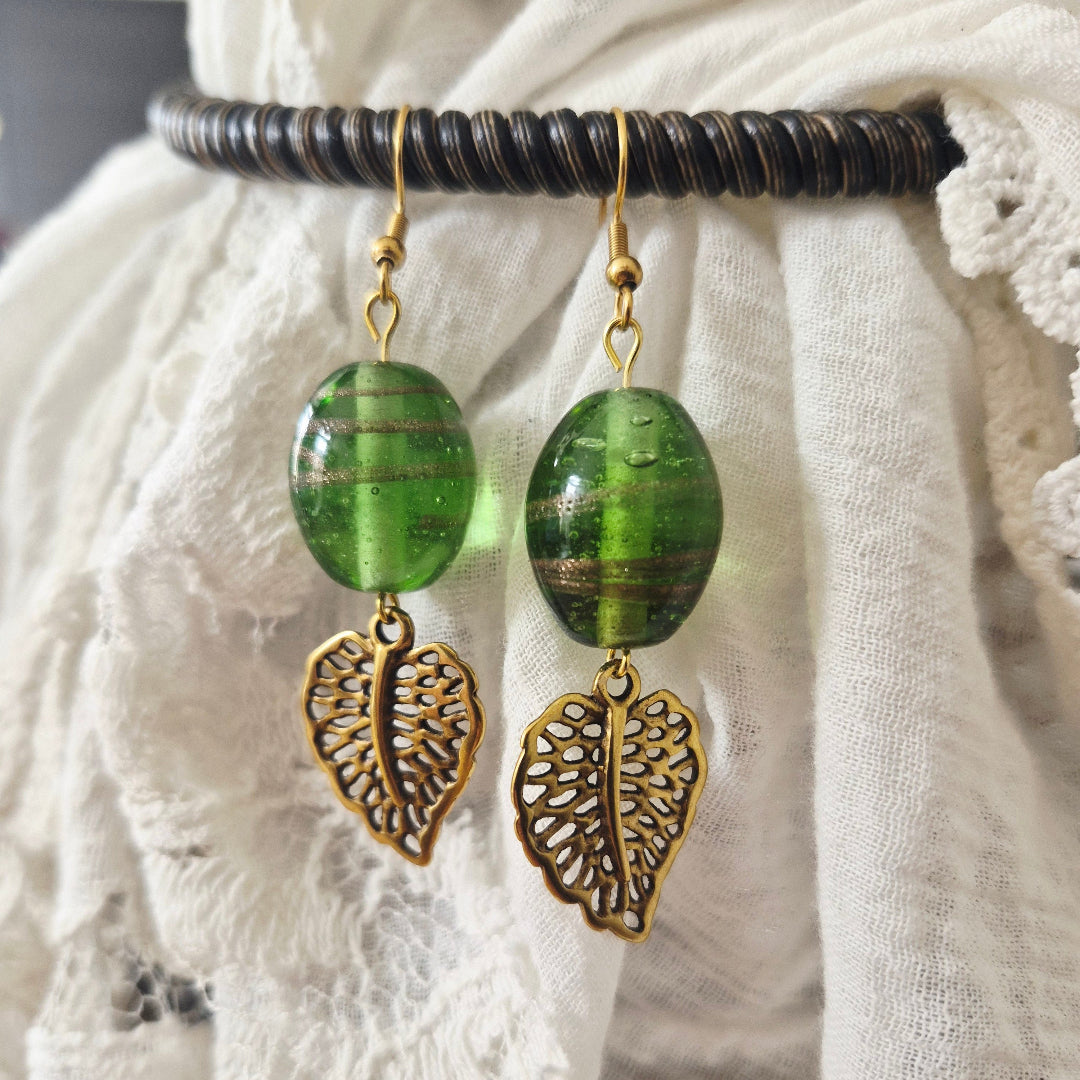 Handgemaakte oorbellen goud groen met Indiase glaskraal en bladbedeltje, one of a kind bij Little Suzies