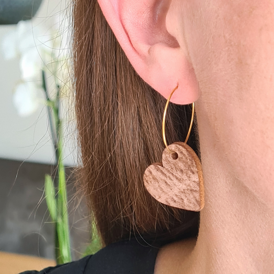 Unieke oorbel van stainless steel met leren hart in goudkleurige ring