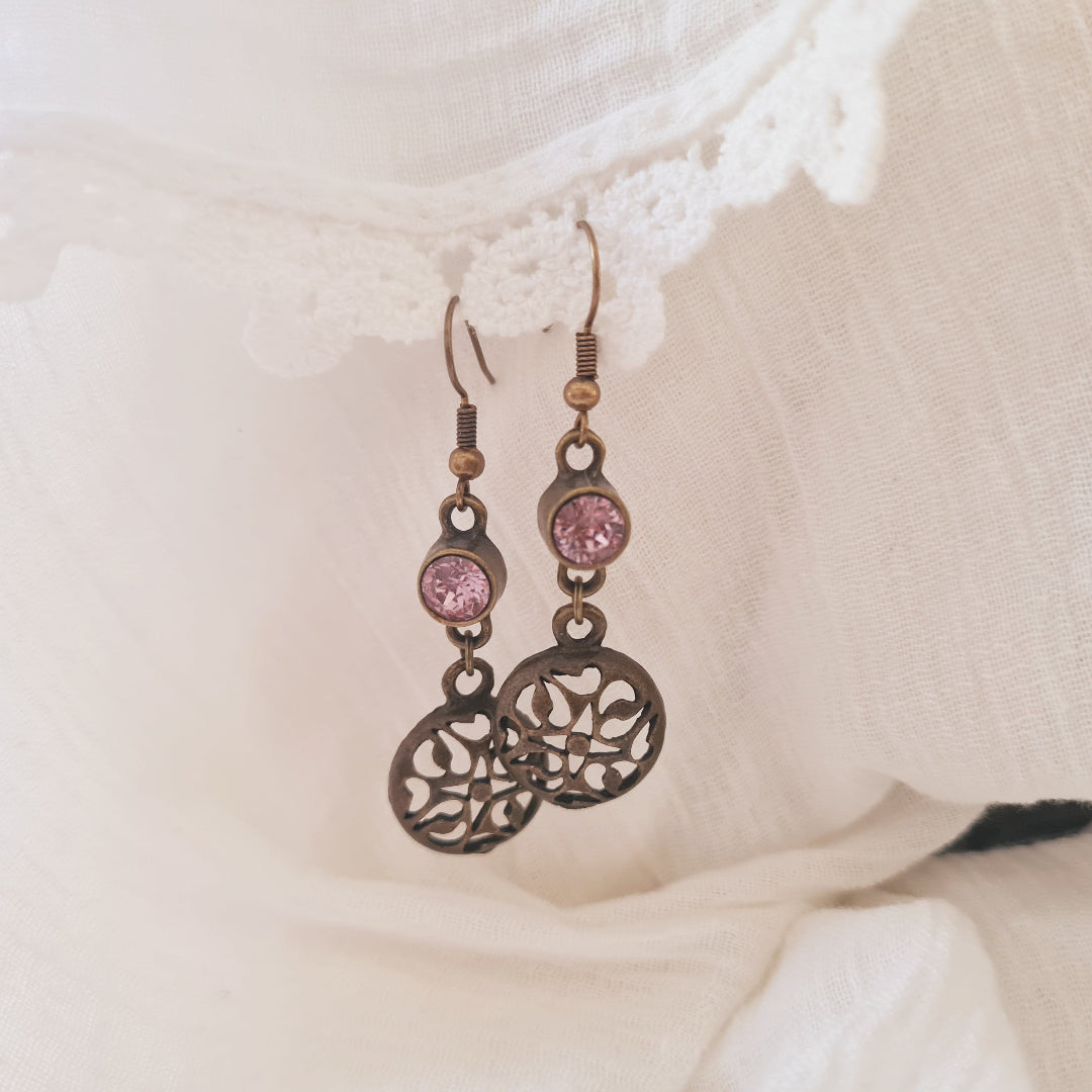 Bronskleurige oorbellen met open hanger en roze kristalglas steentje