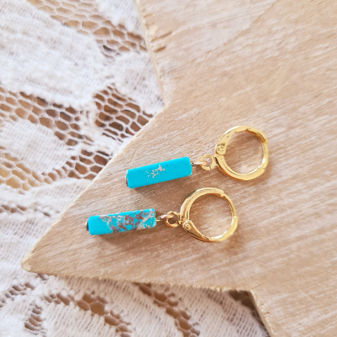 Goudkleurige oorbellen met smal staafje van blauw regaliet aan klapring