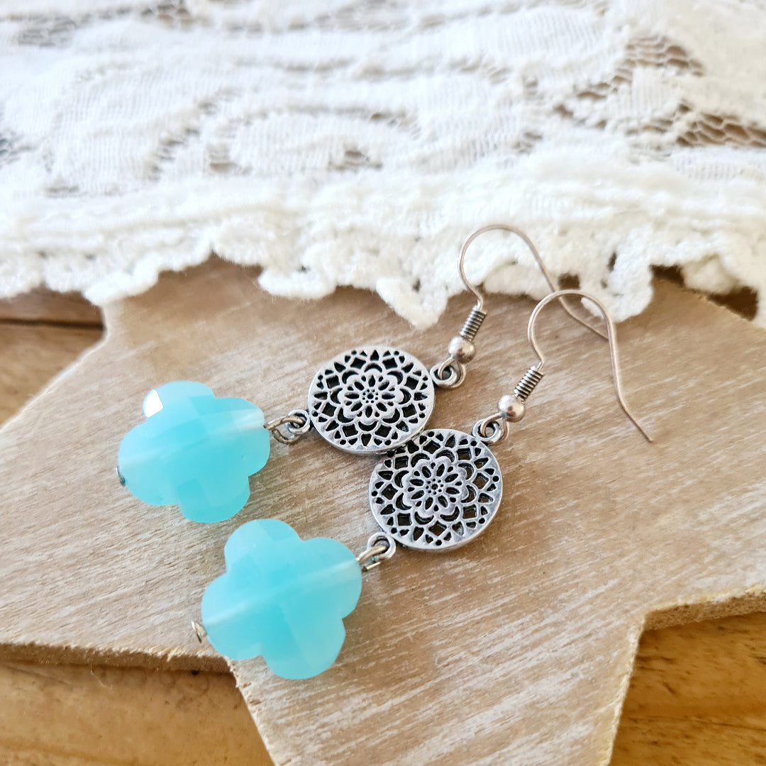 Zilverkleurige oorbellen met aquablauwe klaversteen en mandala-bedel