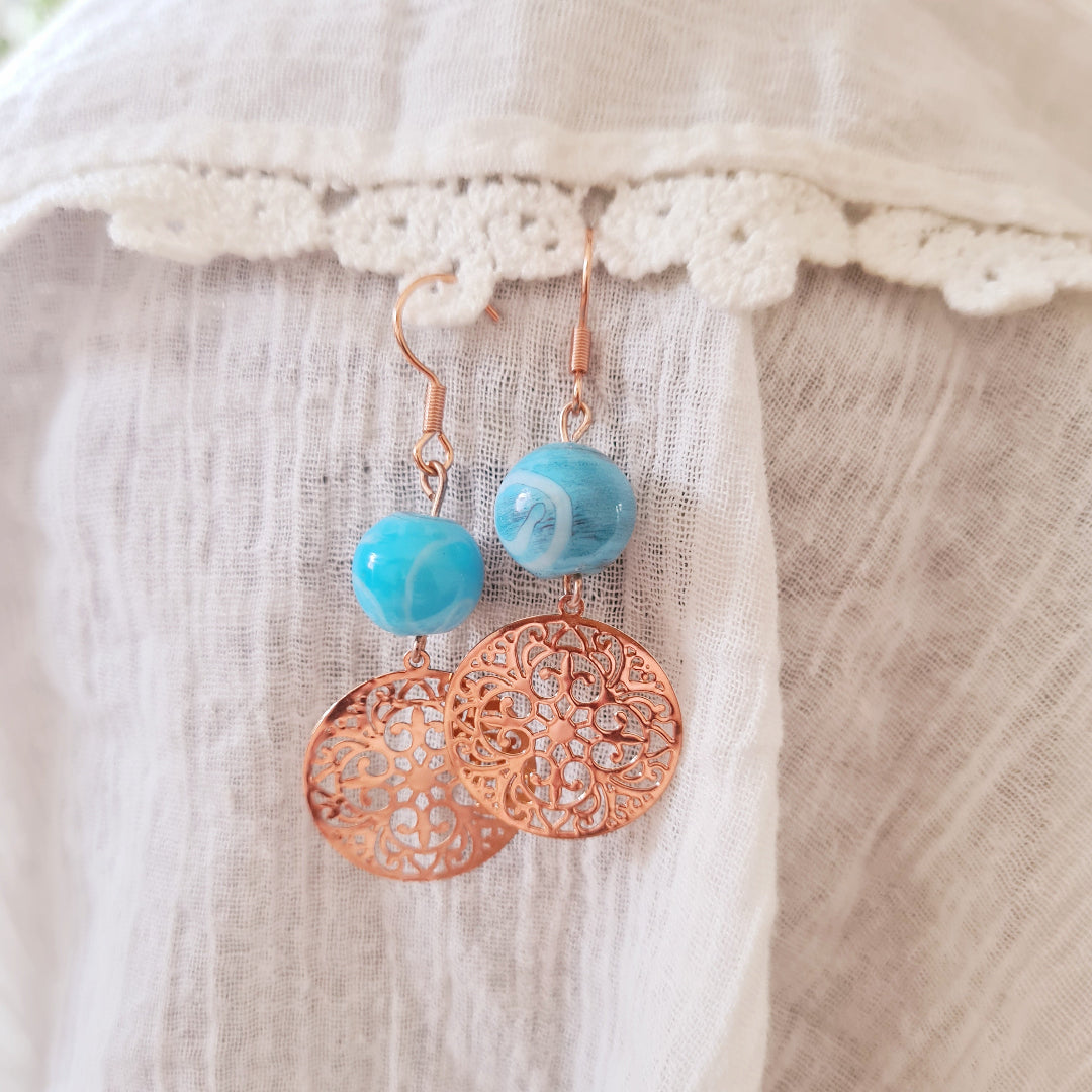 blauw roségoud oorbellen met filigraan bedel en glaskraal