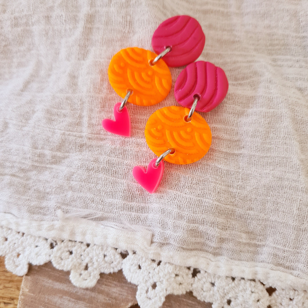 Speelse oorbellen van klei met stekertje en opvallend neon hartje