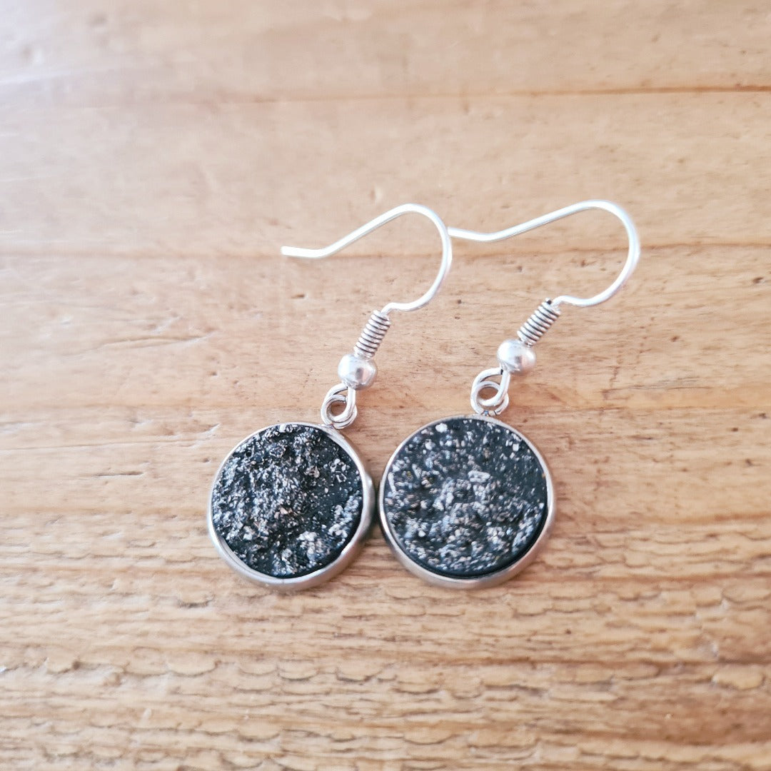 Zilverkleurige oorbellen zwarte glittersteen cabochon gestructureerd