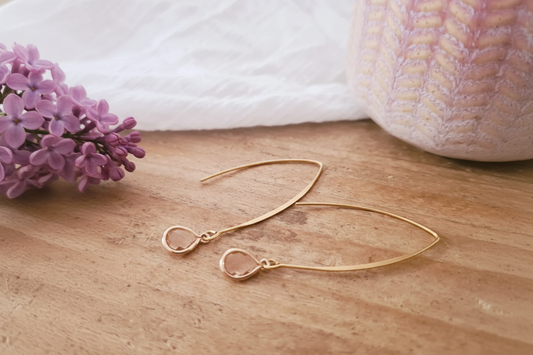 Lange goudkleurige oorbellen met roze kristalglas bedel