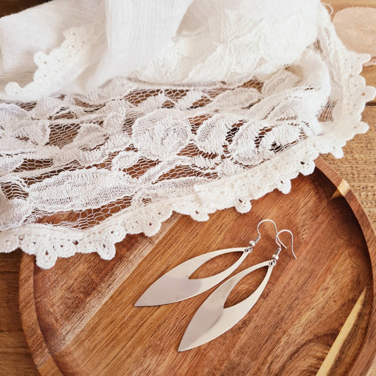 Elegante lange zilveren oorbellen met open bladvorm