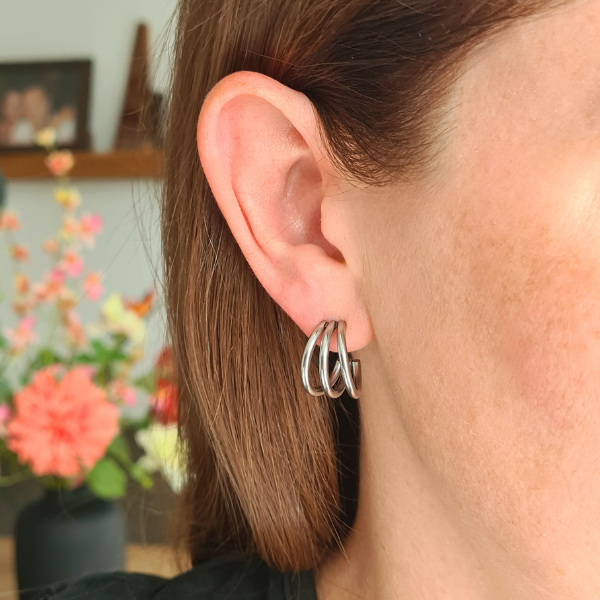 Zilverkleurige stainless steel oorring met driedubbele hoop gedragen