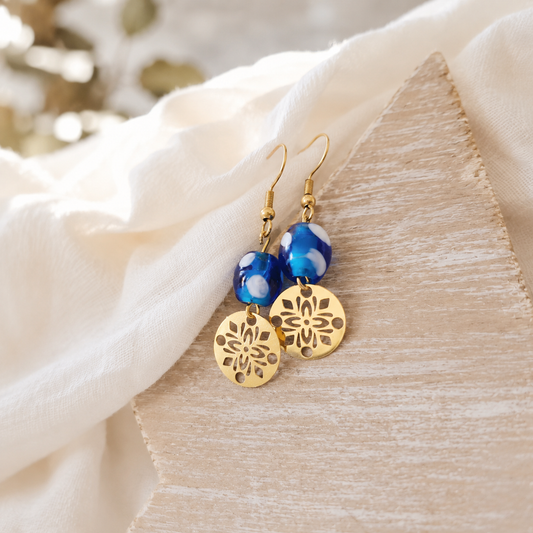 One of a kind oorbellen in goud met boho bedel en blauwe glaskraal