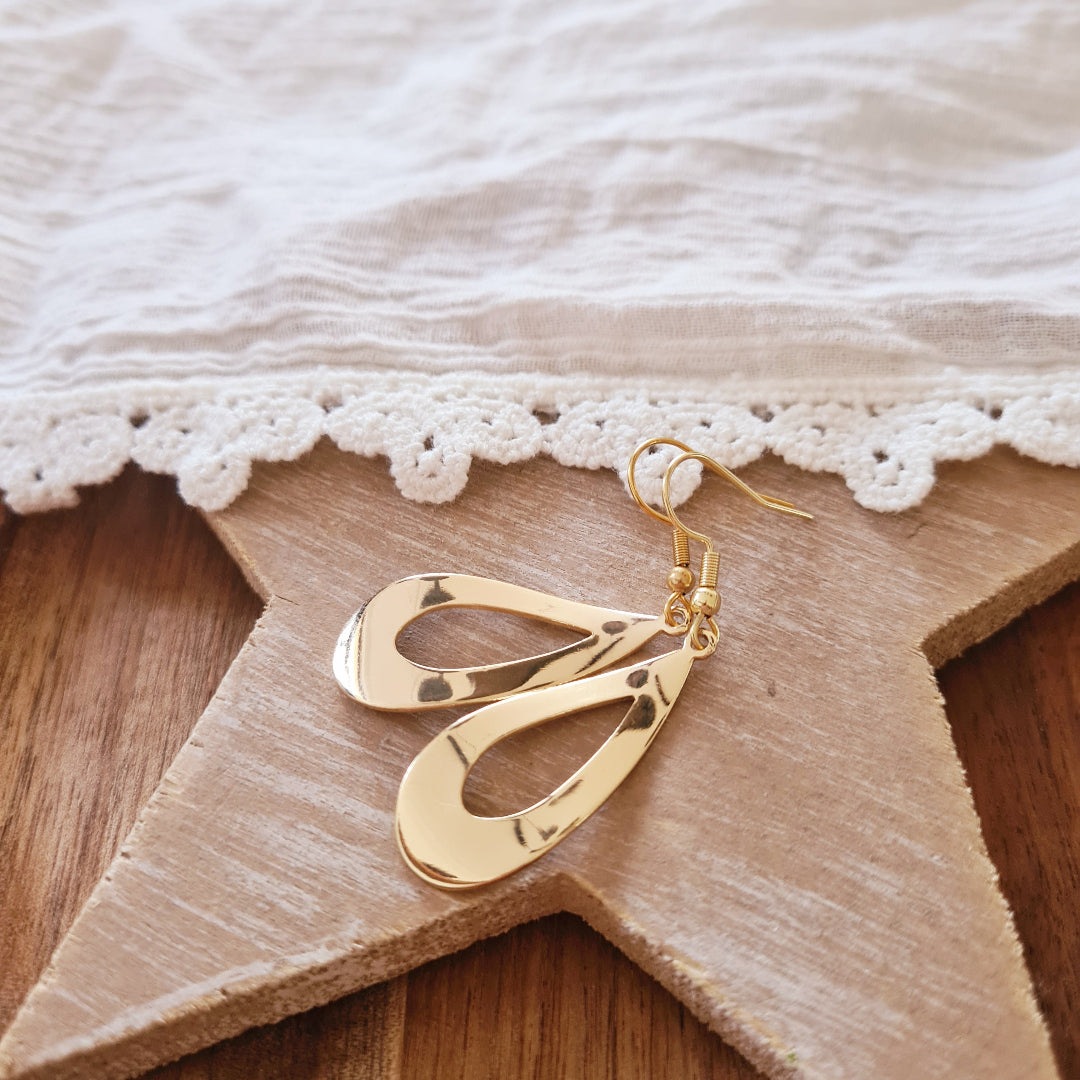 Gouden druppel oorbellen met golvende vorm en glanzende afwerking