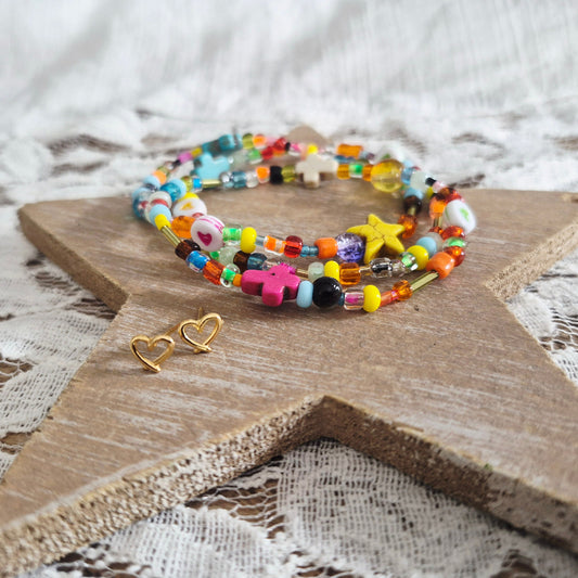 Handgemaakte Ibiza kralenarmband met kleurrijke kralen en gouden hartjes stekertjes oorbellen op houten ster