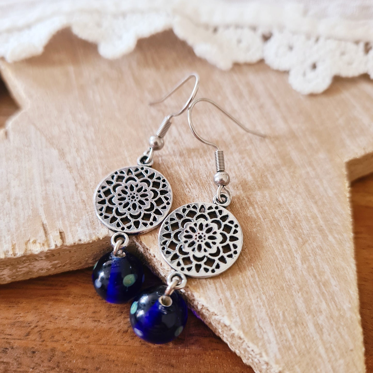 One of a kind oorbellen met blauwe glaskraal uit India en zilverkleurige mandala bedel