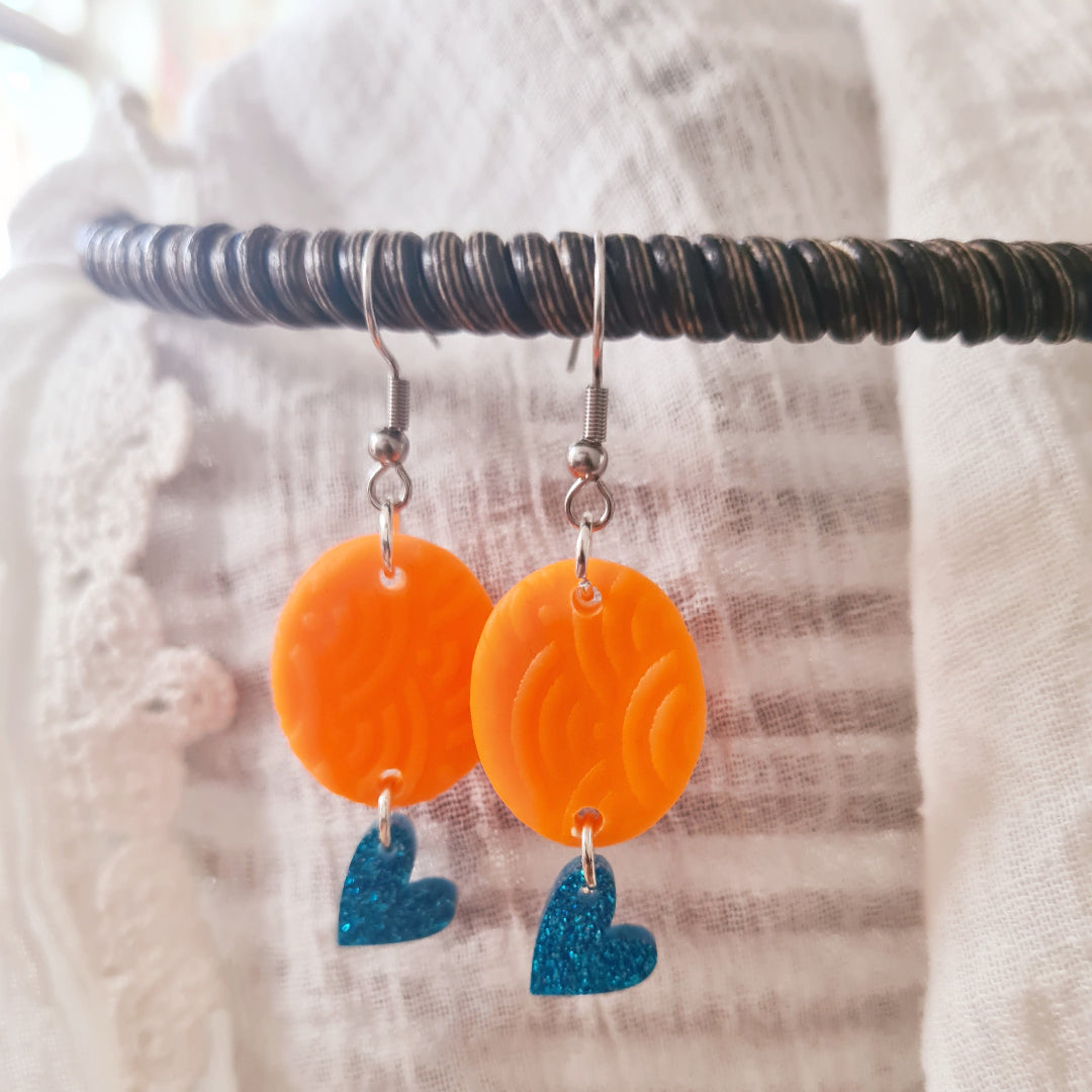One of a kind polymeerklei oorbellen met neon oranje bedel en blauw glitter hartje