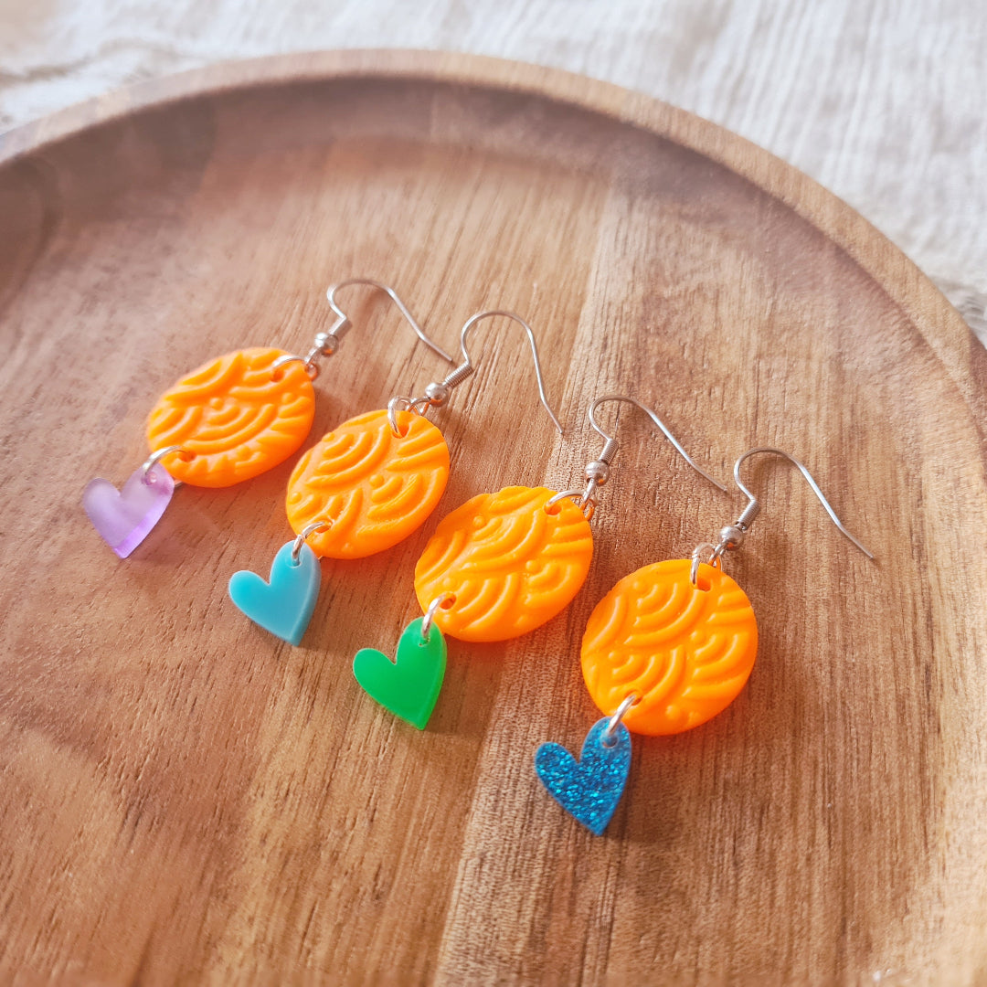 Polymeerklei oorbellen met neon oranje bedel en plex hartje in verschillende kleuren