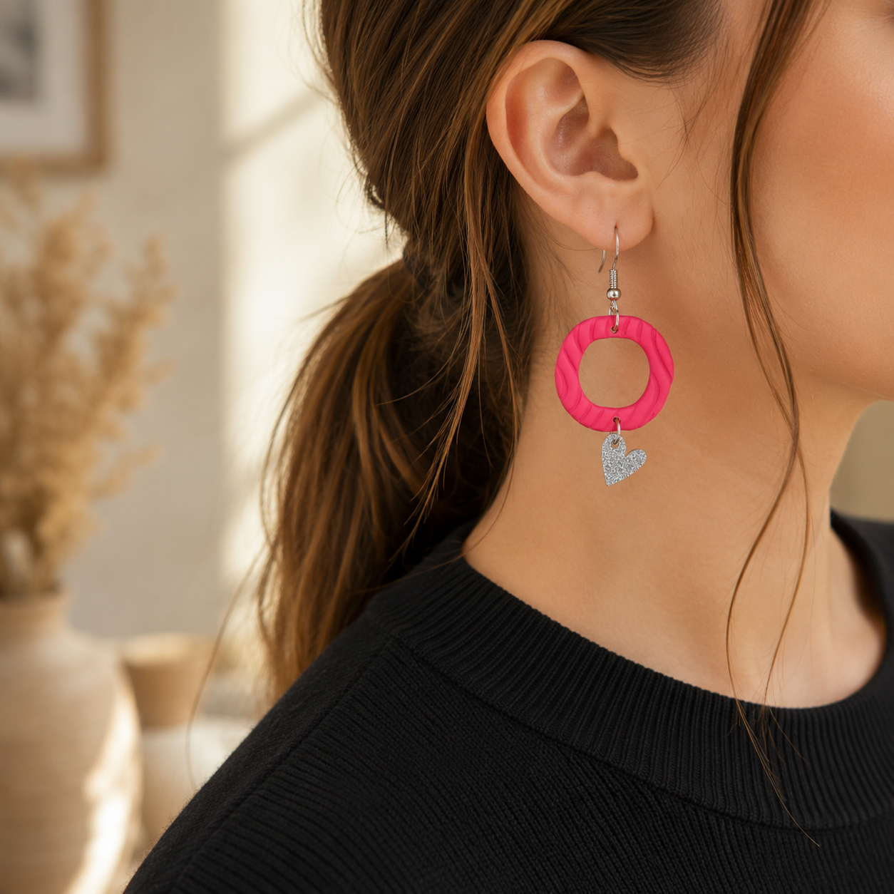Roze polymeerklei oorbellen met zilverglitter hartjesbedel gedragen aan oor