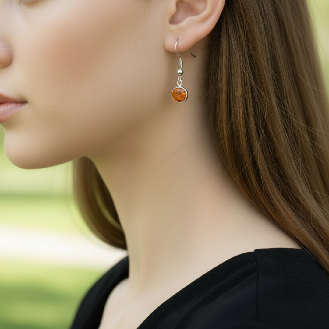 Gedragen zilverkleurige oorbellen met oranje kristalglas, close-up profiel shot nikkelvrije hangeroorbellen