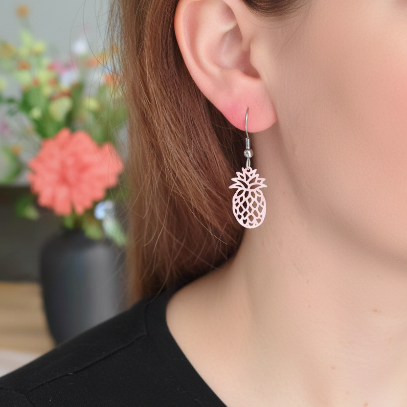 Gedragen zilverkleurige oorbellen met roze ananasbedel, close-up profiel