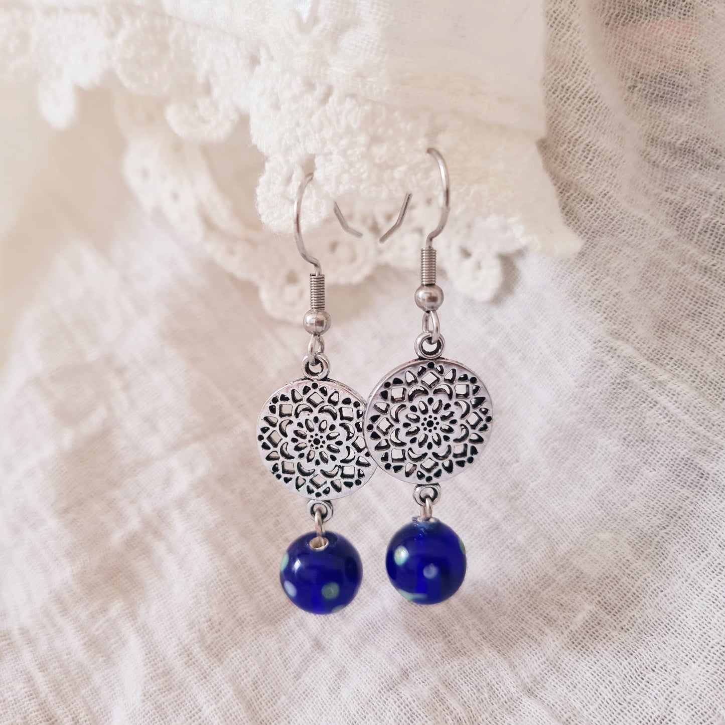 One of a kind oorbellen met blauwe glaskraal uit India en zilverkleurige mandala bedel