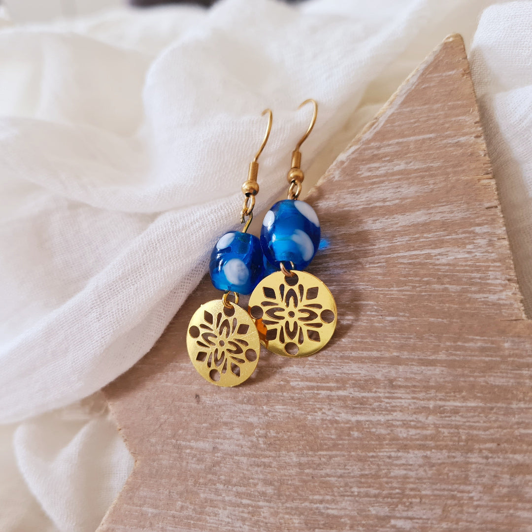 One of a kind oorbellen in goud met boho bedel en blauwe glaskraal