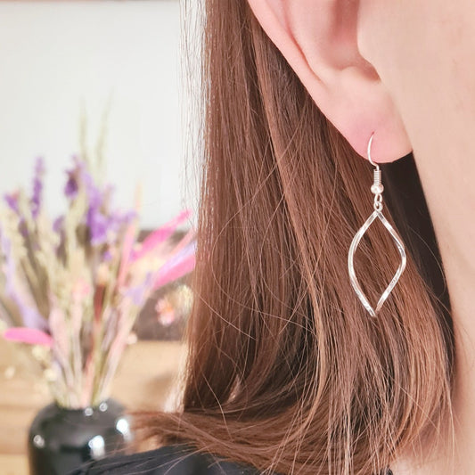 Gedraaide zilverkleurige druppel oorbellen op wit met subtiele draaiing en elegante glans