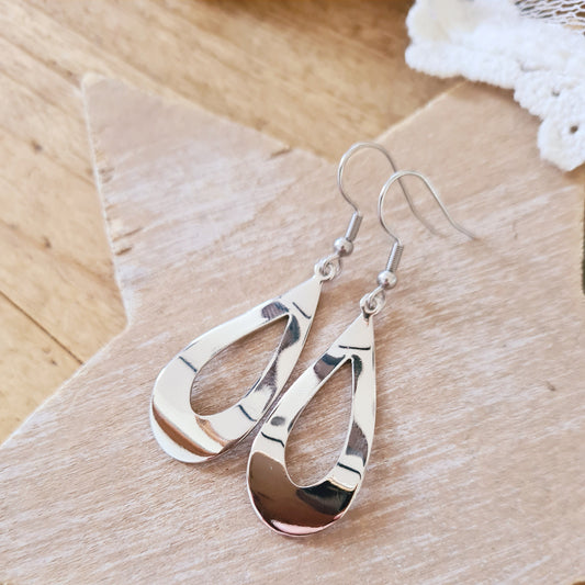 Zilverkleurige druppel oorbellen met golvende vorm en glanzende afwerking