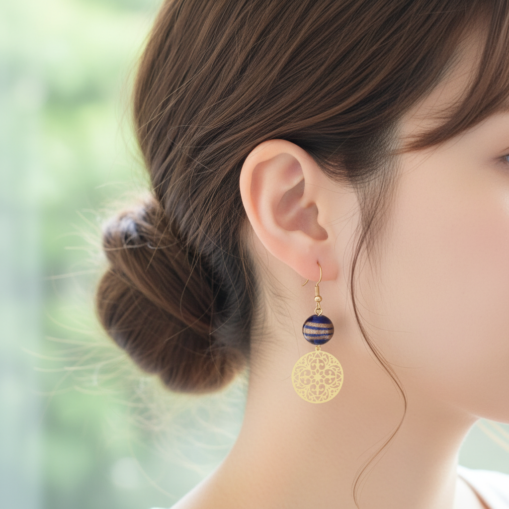 Gouden oorbellen one of a kind met blauwe kraal en boho bedel