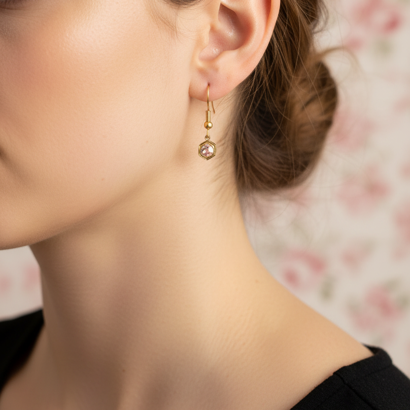 Goudkleurige lichtroze geboortesteenoorbel oktober - gedragen zonder oog