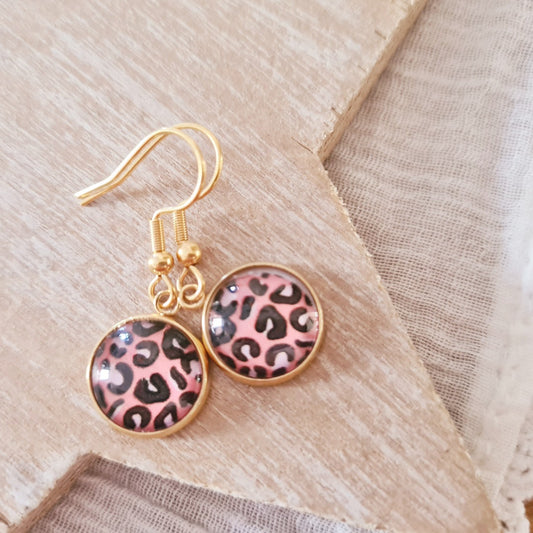 Goudkleurige hangertjes met roze leopardprint op witte ondergrond, kleine speelse oorbellen met panterprint en gouden haaksluiting