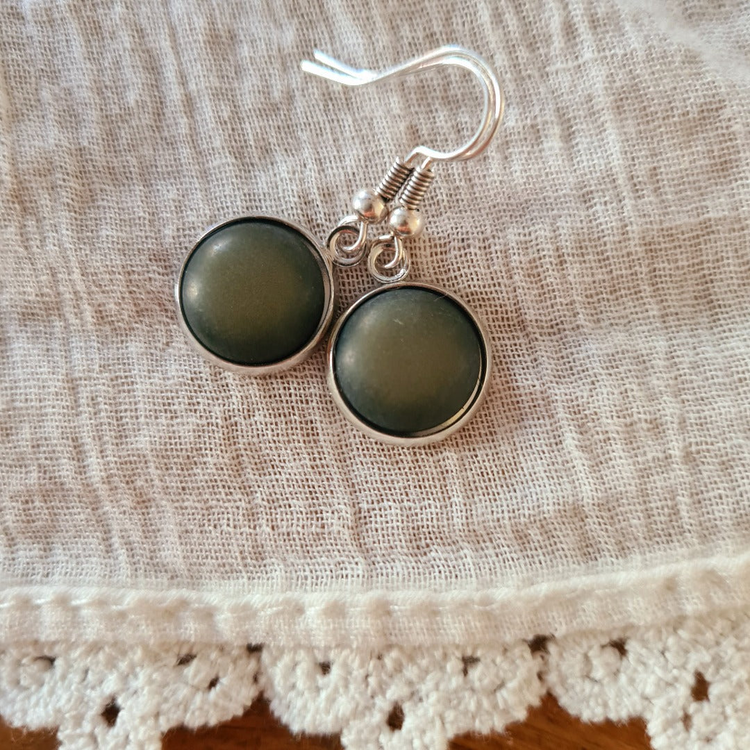 Detailfoto zilverkleurige oorbel met donkergroene ronde cabochon steen