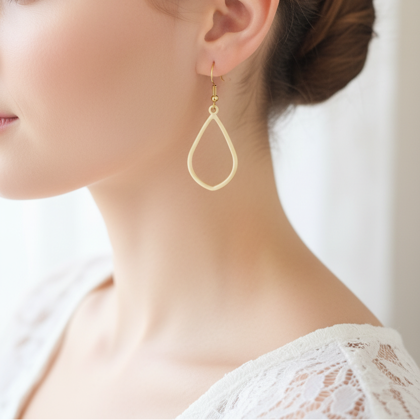 Model draagt matgouden druppel oorbellen met speels elegant design, veelzijdige statement oorbellen