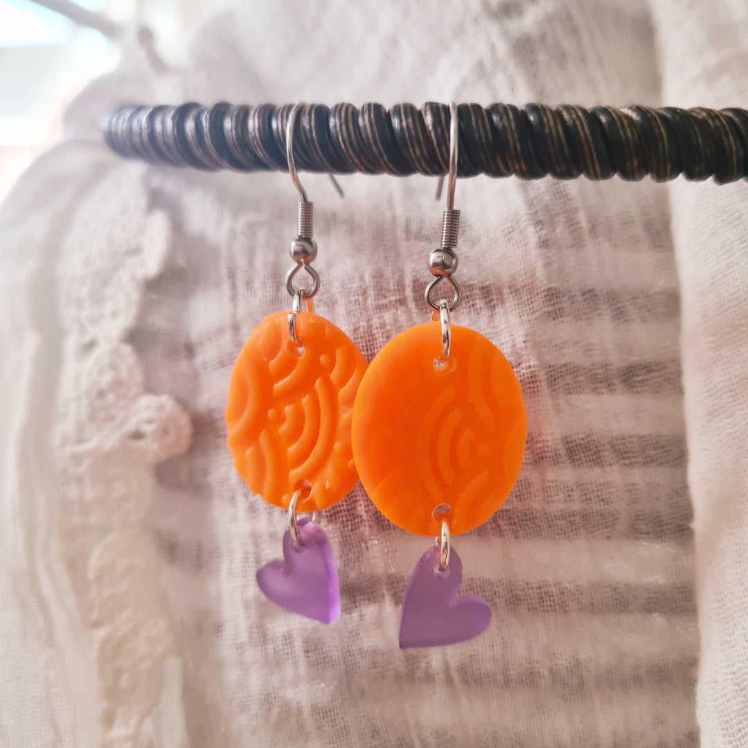Lichte polymeerklei oorbellen met neon oranje hanger en paars plex hartje