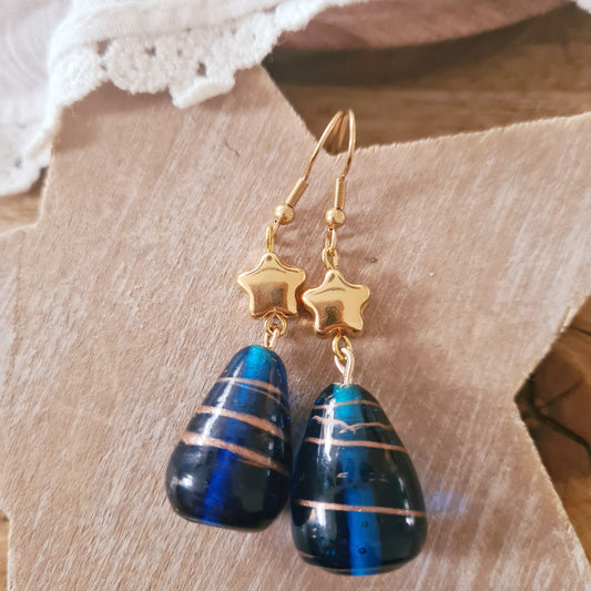 One of a kind oorbellen met donkerblauwe glassteen en gouden sterbedel