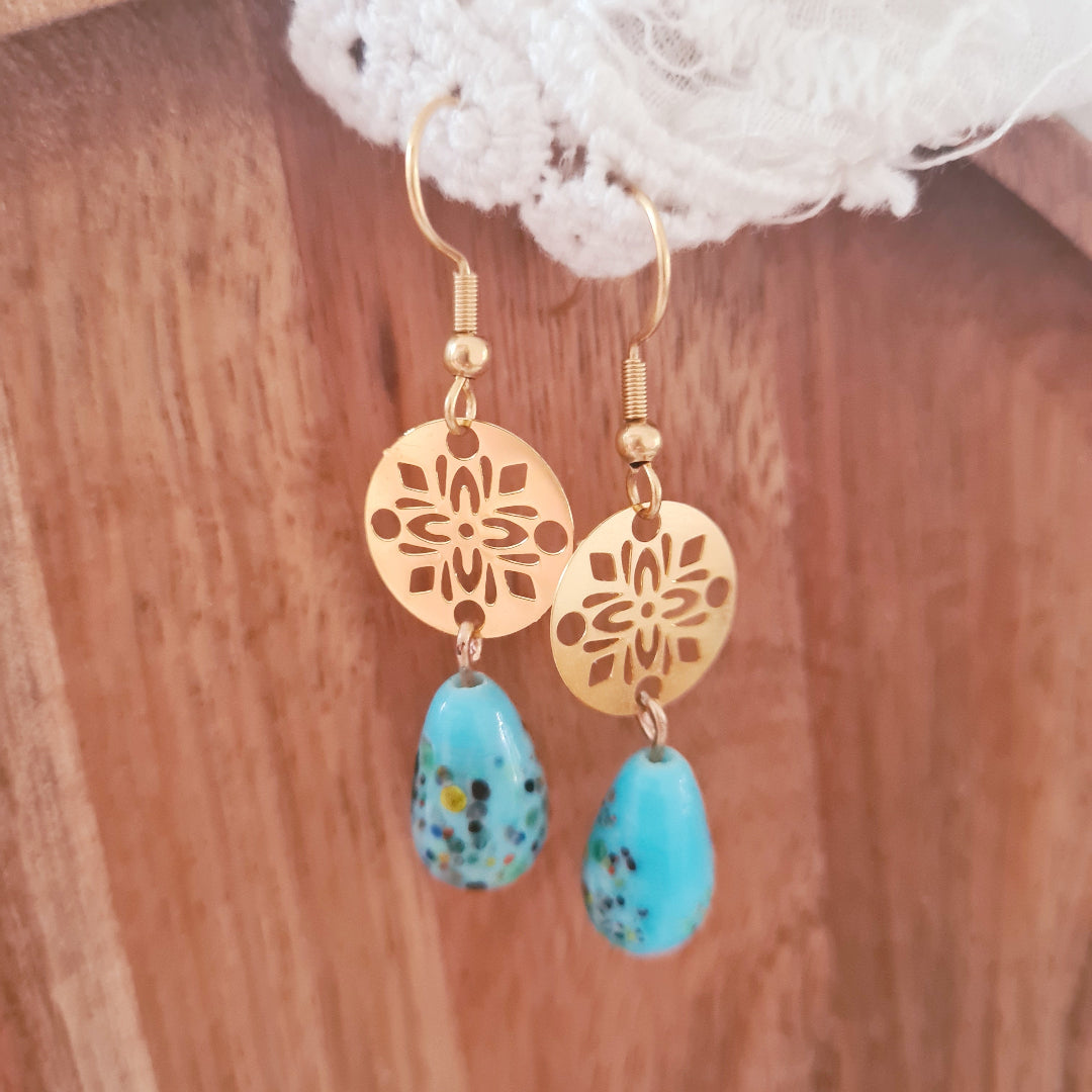 One of a kind oorbellen met lichtblauwe glassteen en gouden bedel