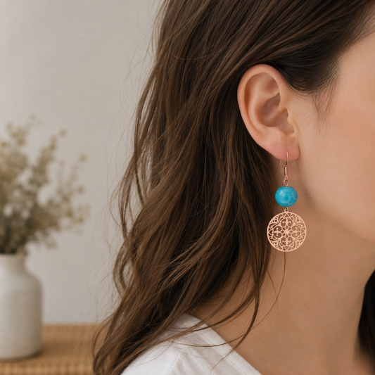 one of a kind oorbellen met blauwe glaskraal en rosegouden filigraan bedel