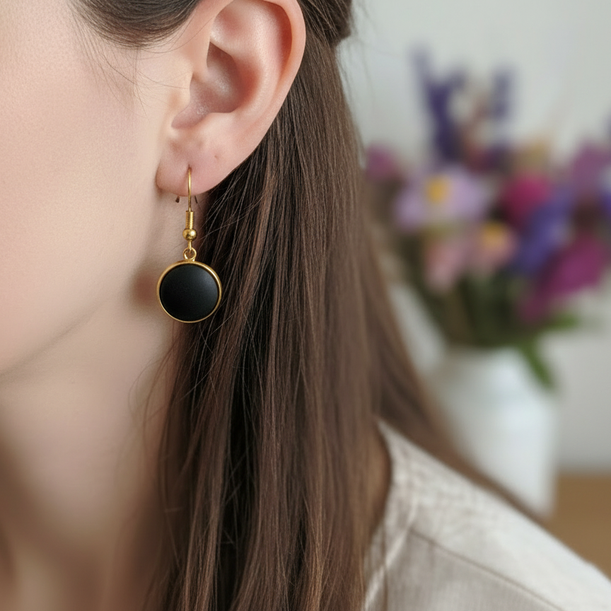 Korte oorbellen met matzwarte steen in goud gedragen door model close-up