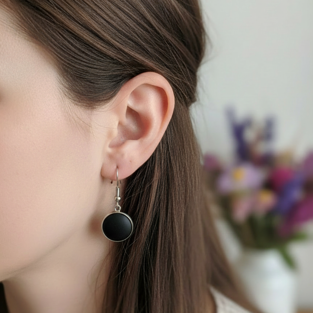 Korte oorbellen met matzwarte steen in zilver gedragen door model close-up