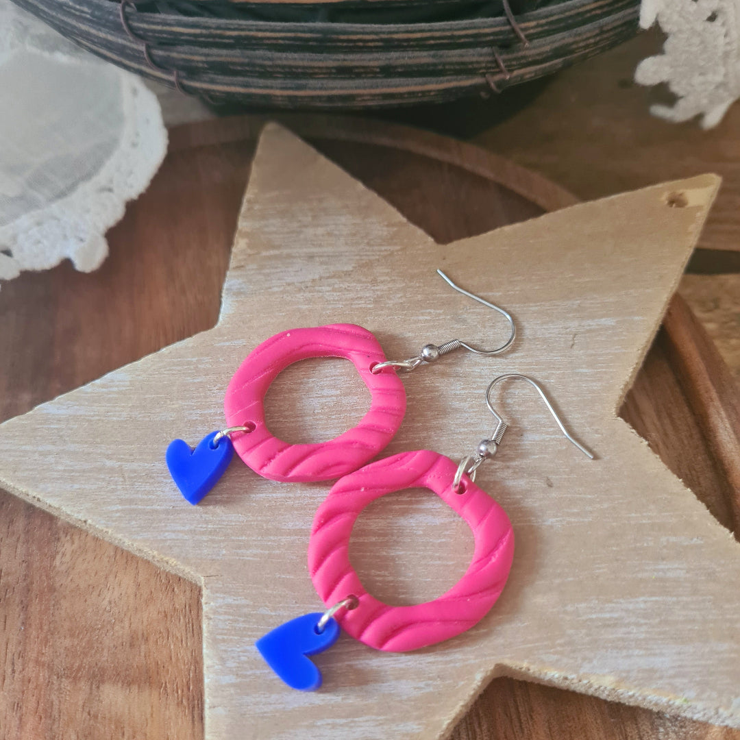 Handgemaakte roze polymeerklei oorbellen met blauw hartjesbedel