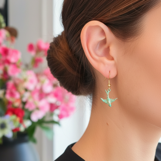 Turquoise vogel oorbellen met geoxideerde gouden look gedragen door model, close-up profiel
