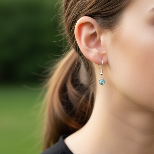 Model draagt zilveren oorbellen met lichtblauwe geboortesteen maart, elegante geboortesteen oorbellen gedragen