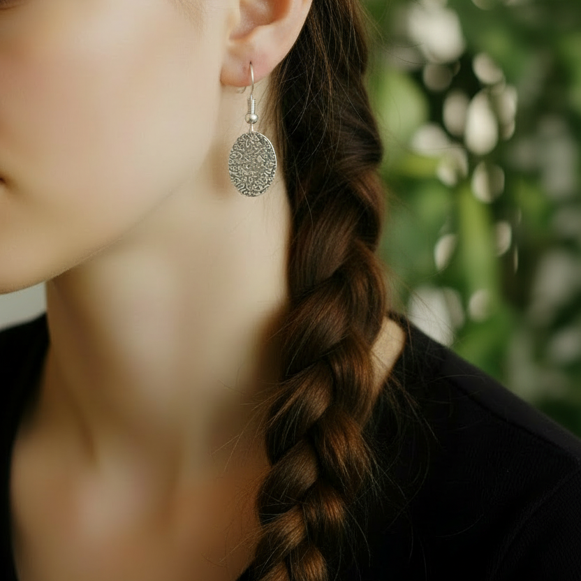 Zilverkleurige gehamerde ovale oorbellen - groene achtergrond