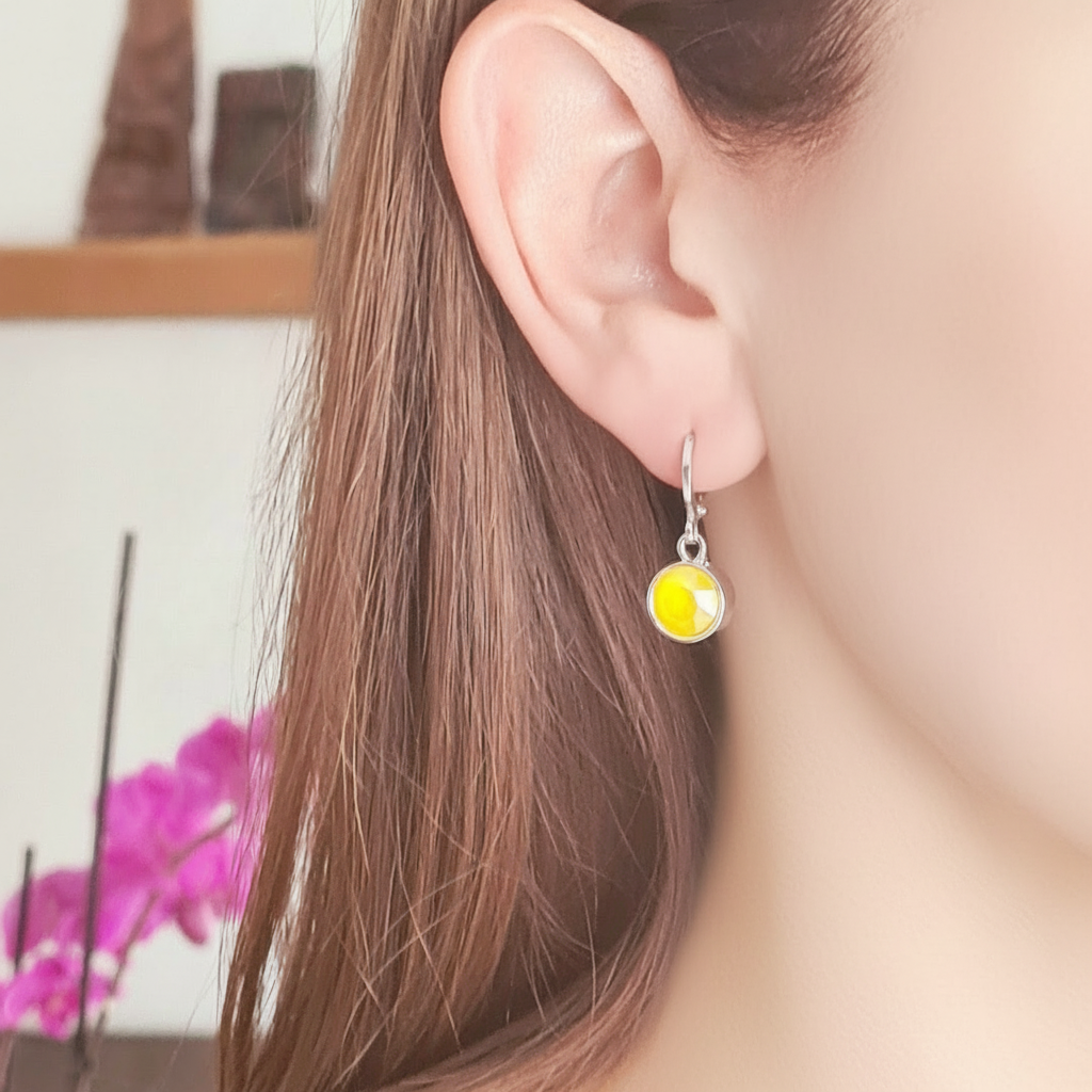 Gedragen zilverkleurige ringetjes met geel kristal, korte klikoorbellen nikkelvrij