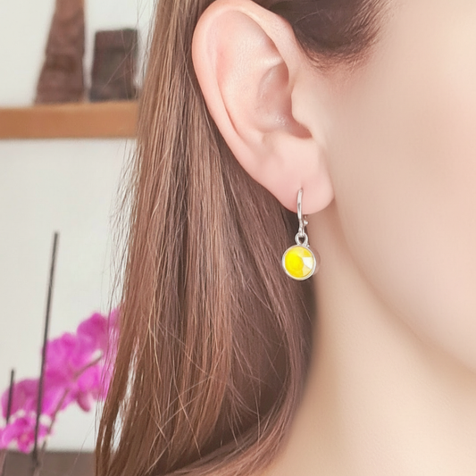 Gedragen zilverkleurige ringetjes met geel kristal, korte klikoorbellen nikkelvrij