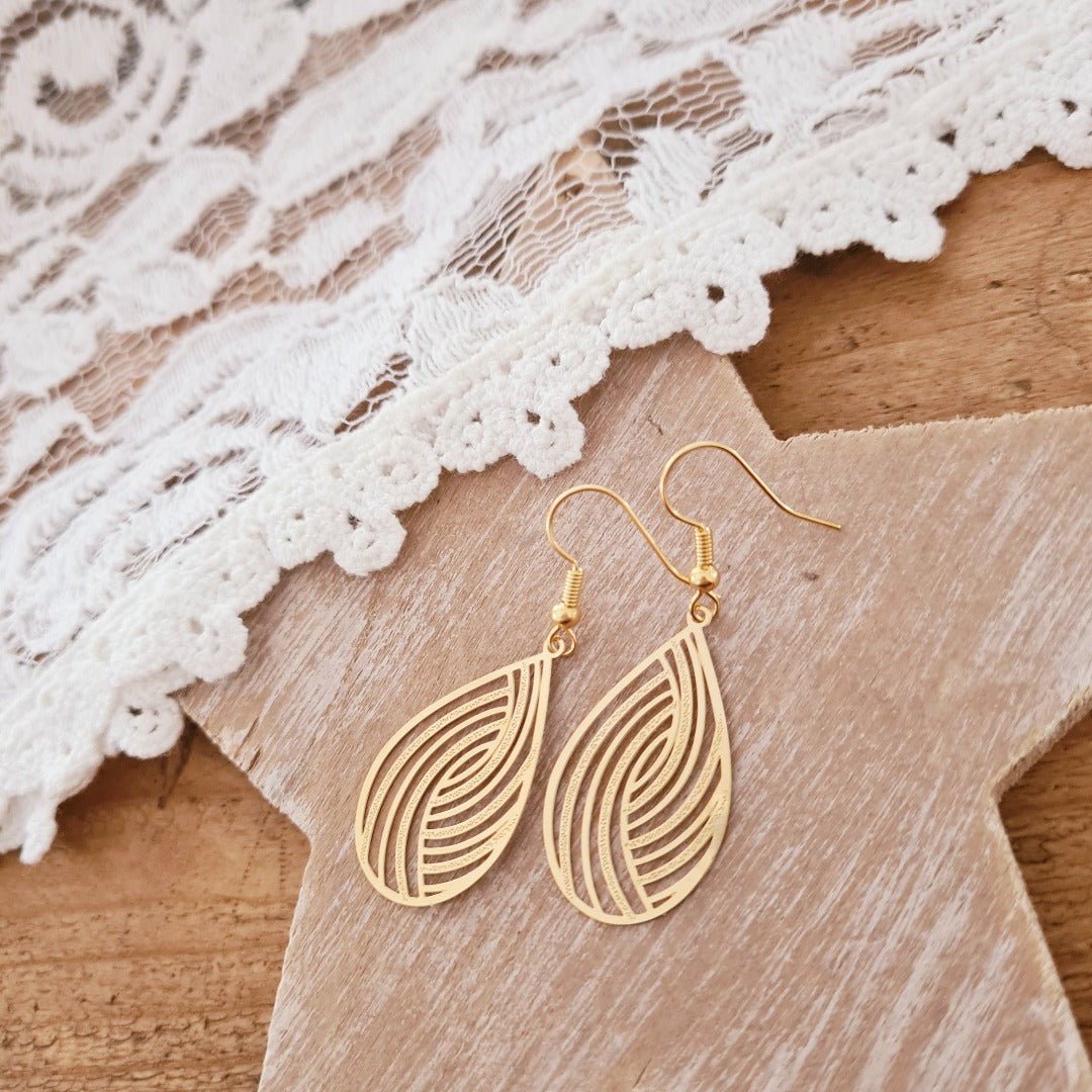 Gouden druppel oorbellen met sierlijk lijnenspel gedragen, elegante look