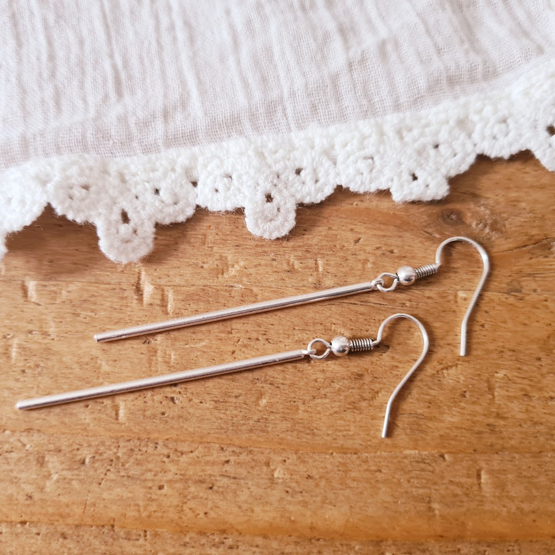 Detailfoto lange zilverkleurige oorhanger, slanke vorm met roestvrij stalen oorhaakje