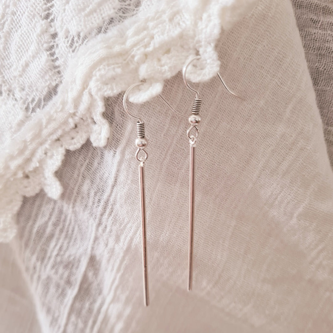 Gedragen lange zilverkleurige oorhanger, minimalistisch design voor een moderne elegante look